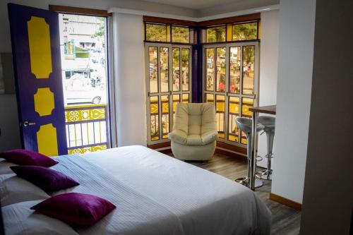 a bedroom with a bed and a chair and windows at Hotel Junior Plaza in Apía