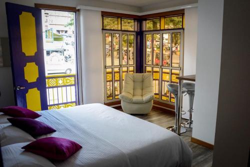 1 dormitorio con 1 cama, 1 silla y ventanas en Hotel Junior Plaza en Apía