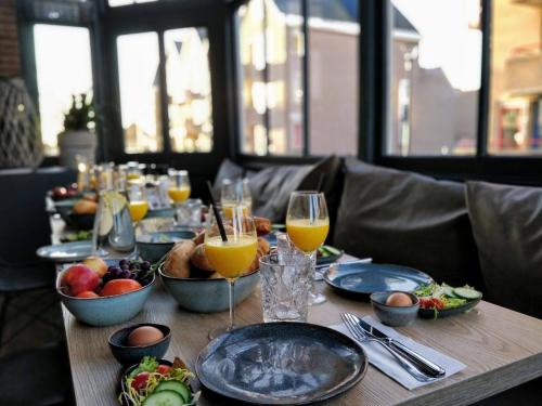einen Tisch mit Teller mit Lebensmitteln und Gläsern Orangensaft in der Unterkunft Het Spoorhuis Uithoorn in Uithoorn