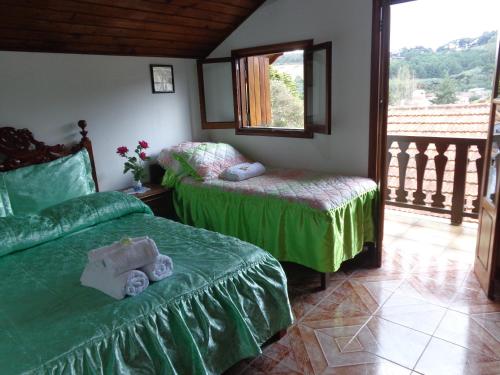 a bedroom with two beds with green sheets and a window at Recanto Monte Verde in Monte Verde