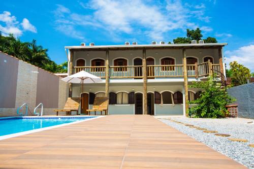 a villa with a swimming pool and a house at Pousada da Árvore in Boicucanga