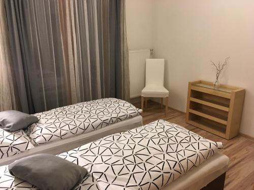 Habitación con 2 camas y una silla. en Penzion Svatava, en Ostrava