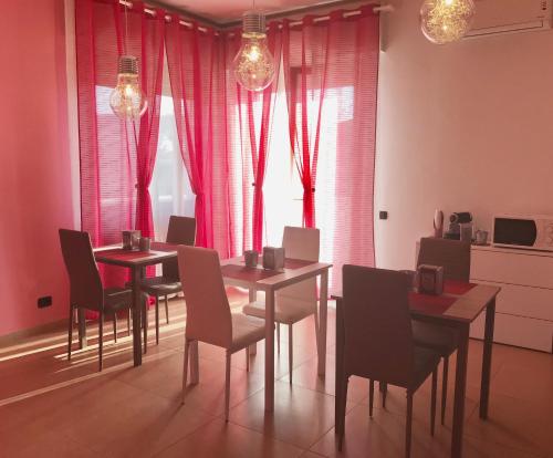 une salle à manger avec des rideaux roses, des tables et des chaises dans l'établissement Color House Malpensa B&B, à Cassano Magnago