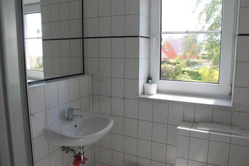 a white tiled bathroom with a sink and a window at Am Ostseestrand in Zingst
