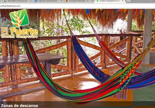 a hammock hanging from a wooden fence with a bench at Hotel Campestre el Fuerte in Rozo