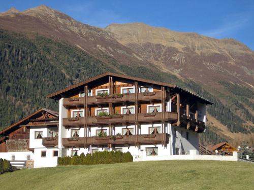 a building on a hill with mountains in the background at ban Kneissl`s in Umhausen