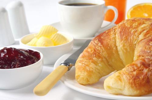 een bord met een croissant, een kop koffie en een kopje bij Chaillac Bed & Breakfast in Chaillac