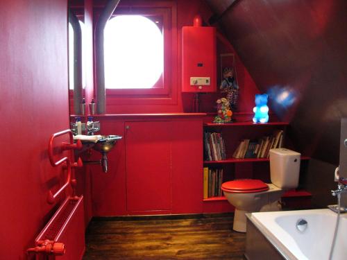 La salle de bains rouge est pourvue de toilettes et d'une fenêtre. dans l'établissement B&B Lady Jane, à Bruges