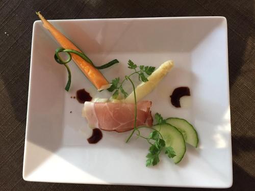 a white plate with meat and vegetables on a table at Hotel Restaurant de l'Europe in Wissembourg