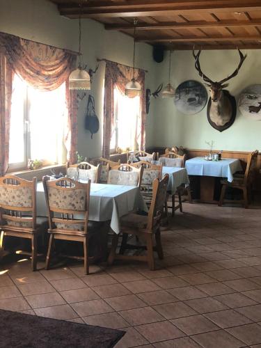 a dining room with tables and chairs and windows at Hotel-Pension Am Mühlberg in Lübbenau