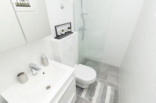 a white bathroom with a toilet and a sink at Apartman Roko in Petrcane
