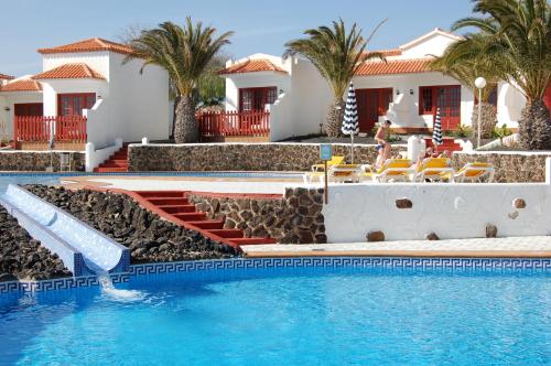 a swimming pool with a pool table and chairs at Bungalows Castillo Beach in Caleta De Fuste