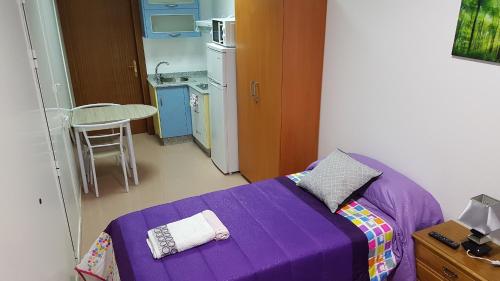 a purple bed in a small room with a kitchen at Apartamento Study 1 Select Real Caldas de Reis in Caldas de Reis