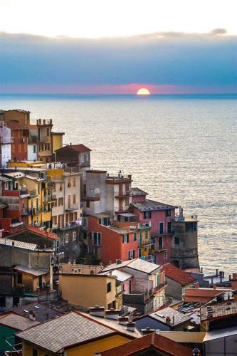 a view of a city with the sun setting over the water at Ines Apartment in Manarola