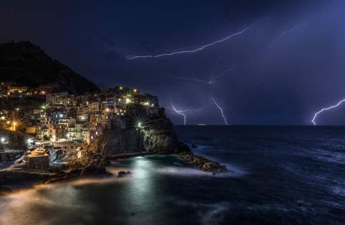a storm over a city with lightning bolts at Ines Apartment in Manarola