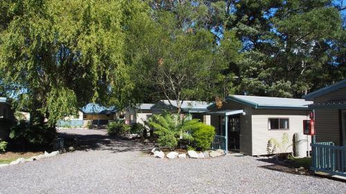 a house with a gravel driveway in front of it at Strahan Retreat Holiday Park in Strahan