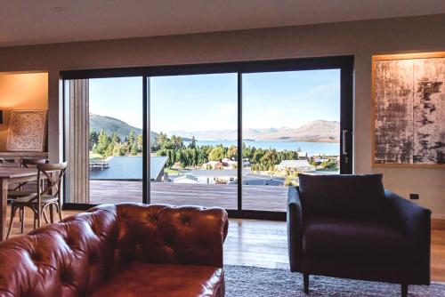 a living room with a leather couch and a large window at The View Lake Tekapo in Lake Tekapo
