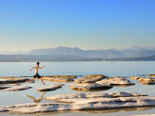 a man running on rocks in the water at B&B Desenzano Paradise in Desenzano del Garda