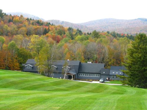 a large house on a hill with a green field at Trailside Inn in Killington
