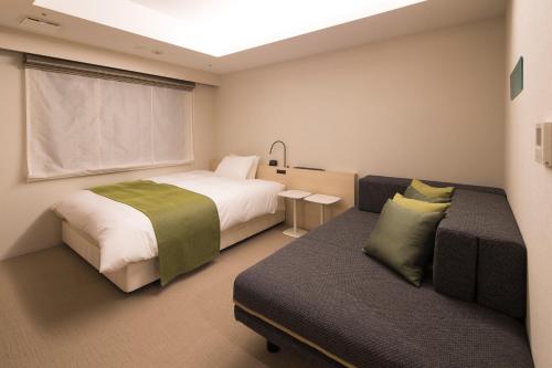 a bedroom with a bed and a couch and a window at Hotel Granbinario Komatsu in Komatsu