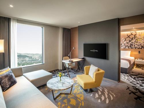 a living room with a couch and a bed and a tv at Novotel Suites Ambassador Seoul Yongsan in Seoul