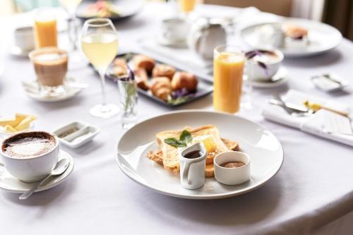 a table with a plate of food and cups of coffee at Novotel Suites Ambassador Seoul Yongsan in Seoul