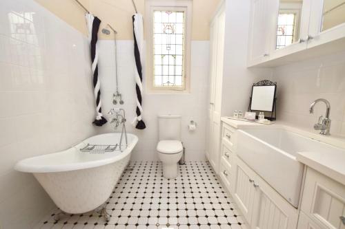a bathroom with a tub and a toilet and a sink at The Church @ Woodford in Woodford