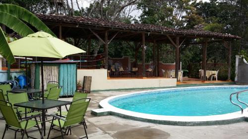 a pool with chairs and a table and an umbrella at Casa La Comarca in Estelí