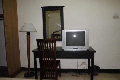 a desk with a television and a chair and a lamp at Simpang Tujuh in Cepu