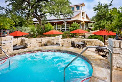 a swimming pool with tables and umbrellas in front of a house at Hyatt Vacation Club at Wild Oak Ranch in San Antonio