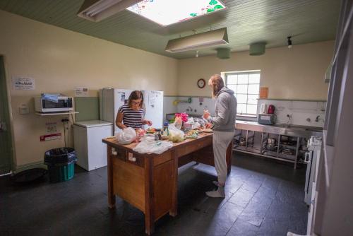 a man and woman in a kitchen preparing food at Port Fairy YHA in Port Fairy