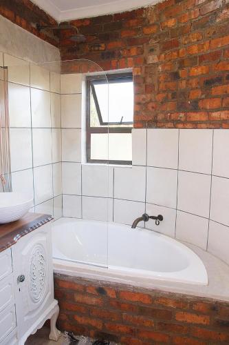 a bath tub in a bathroom with a brick wall at Matusadona Guest Lodge in Hillcrest