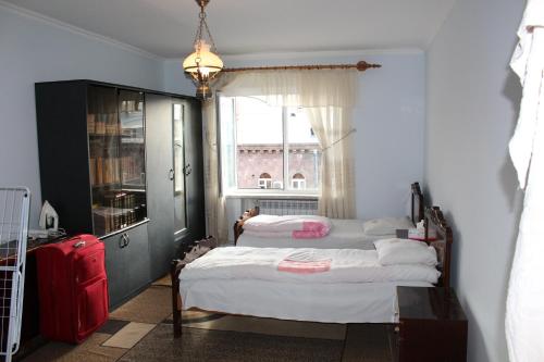 1 Schlafzimmer mit 2 Betten, einem Fenster und einem roten Koffer in der Unterkunft Super Location in Yerevan