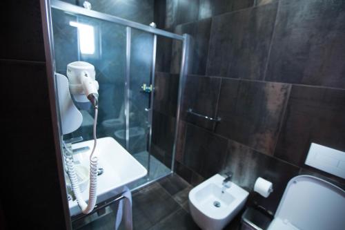 a bathroom with a shower and a sink and a phone at Hotel Palma in Rinas