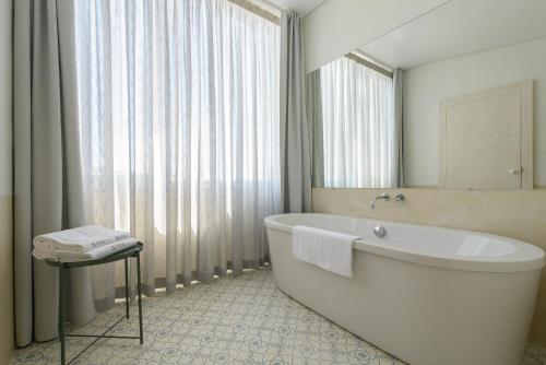 baño con bañera y ventana grande en Dona Graca Lisbon Apartments, en Lisboa