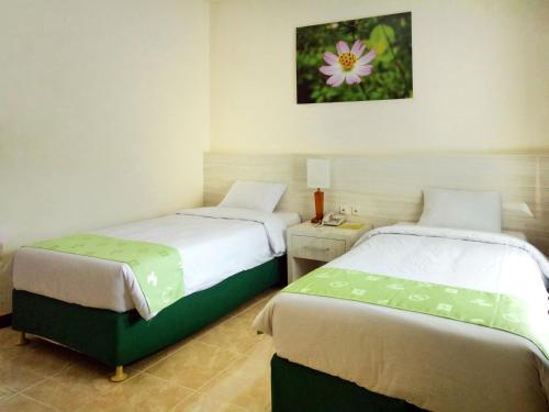a bedroom with two beds and a picture on the wall at Green Garden Hotel in Tuban