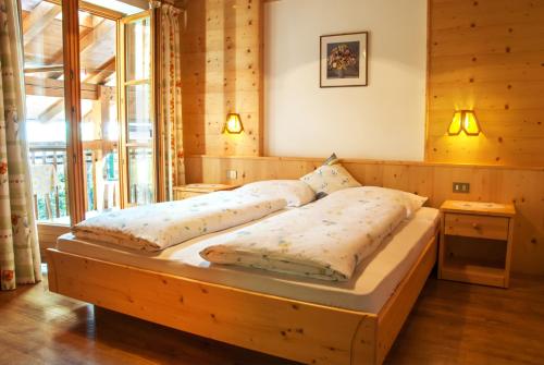 a large bed in a room with wooden walls at Obermairhof in Parcines