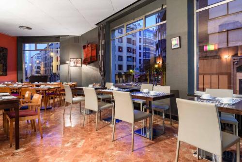 a restaurant with tables and chairs and a large window at Crisol Quindós in León
