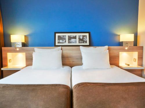 two beds in a hotel room with blue walls at Radisson Hotel Paris Le Bourget in Le Bourget