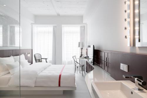 a white bedroom with a bed and a sink at Ruby Coco Hotel Dusseldorf in Düsseldorf