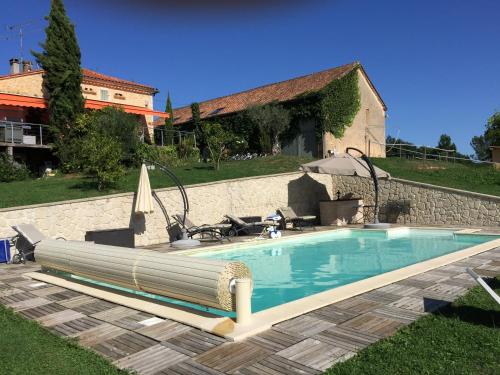 une piscine devant une maison dans l'établissement La ferme de Pouzatel proche Bonaguil, à Fumel