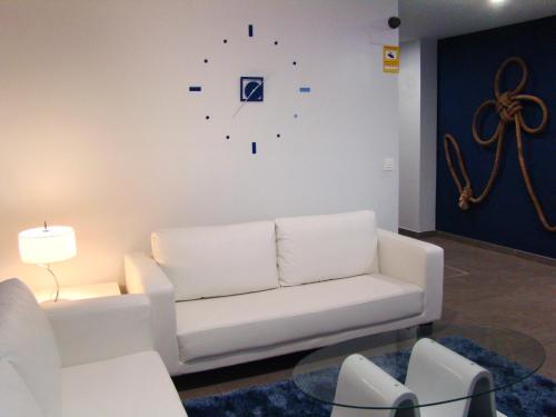 a living room with a white couch and a clock on the wall at Bekale in Ea