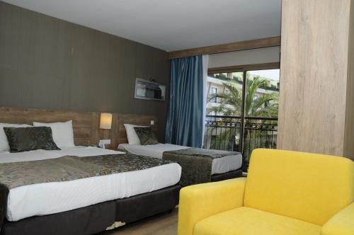 a hotel room with two beds and a yellow chair at Lucida Beach - All Inclusive in Kemer
