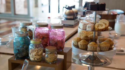 eine Auswahl an Gläsern und Muffins auf einem Tisch in der Unterkunft The Mantrini Chiang Rai in Chiang Rai
