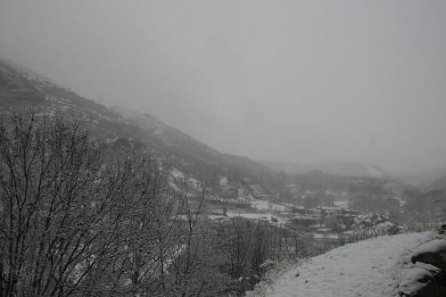 a snow covered hill with a town in the distance at Casa Rural Era de Ferro in Erill la Vall