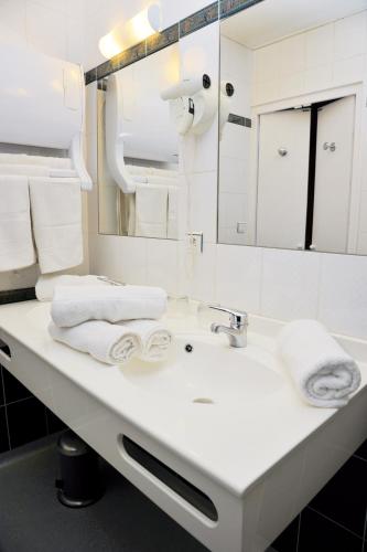 une salle de bain avec un lavabo blanc et un miroir dans l'établissement Hotel du Nord - Ville-Haute, à Saint-Flour