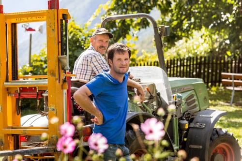 two men are standing next to a tractor at Obermairhof in Parcines