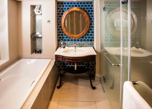 a bathroom with a tub and a sink and a mirror at Southern Sun Maputo in Maputo