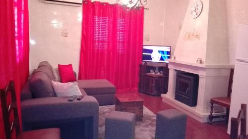 a living room with red curtains and a couch and a television at Casa da tia Bina in Monsaraz