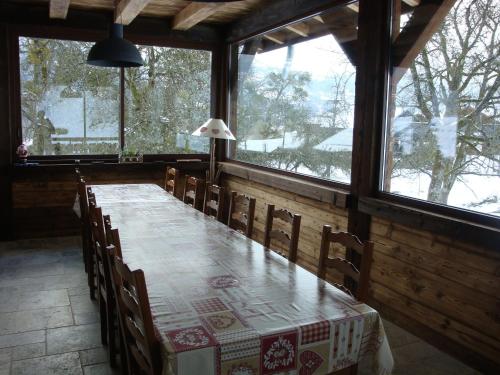 a dining room with a table and some windows at Chambres d'Hôtes Chalet de la Source in Morillon